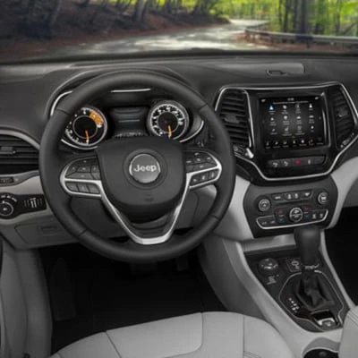 Displaying a new Jeep Cherokee Interior dashboard, steering wheel, center display with screen and controls.