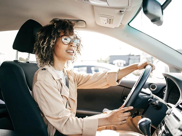 Inside a car with a young woman driving.