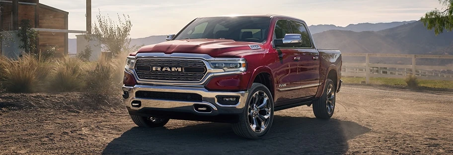 Ram 1500 truck parked on a dirt road near a barn.